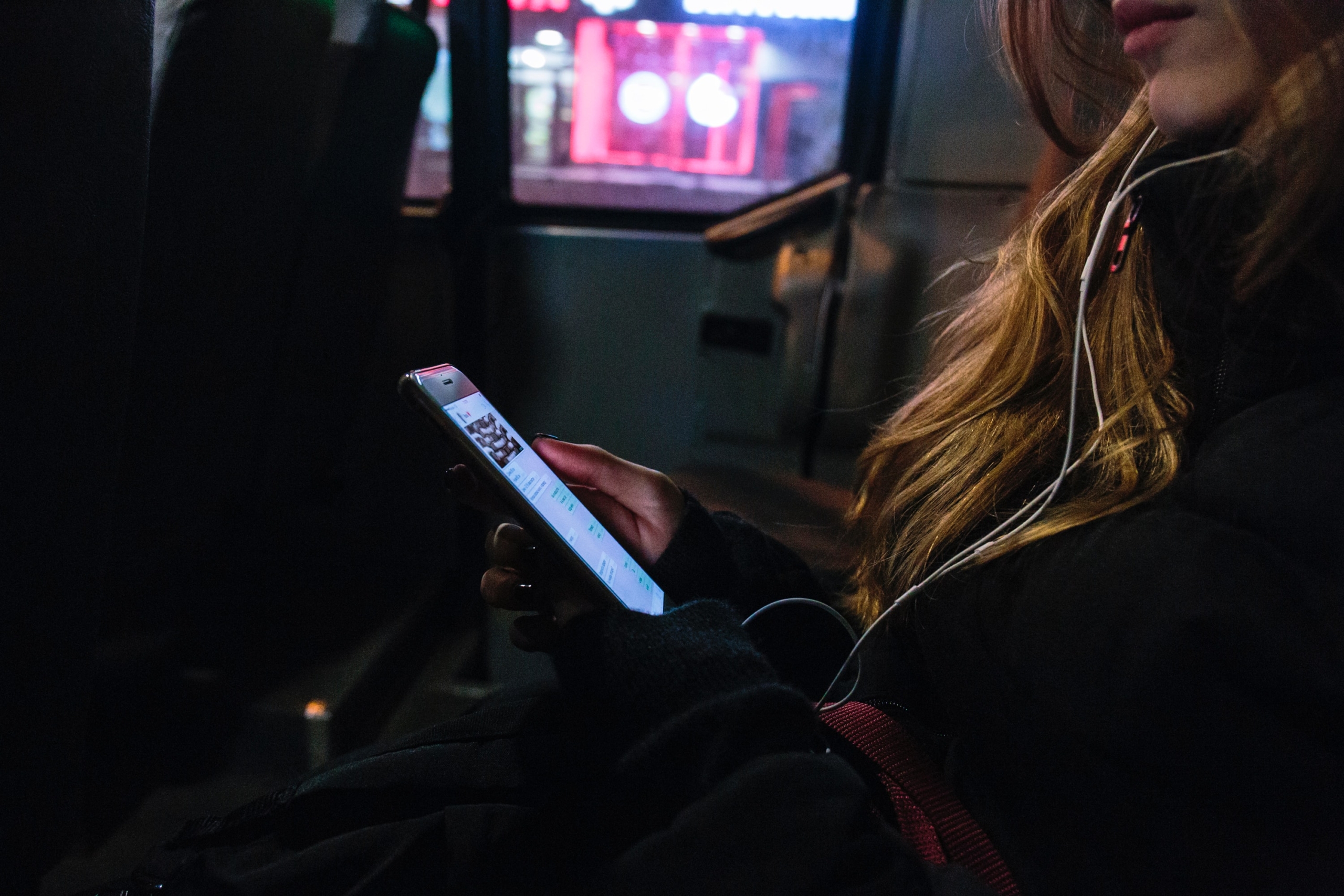 イヤホンしながらスマホゲームをしている女性